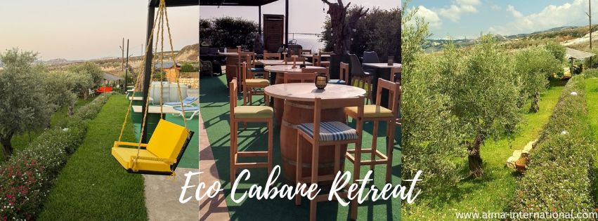 Relaxing outdoor space at Cabane Chekka with a swinging chair, wooden bar, surrounded by olive trees and lush greenery in Lebanon’s Chekka Valley
